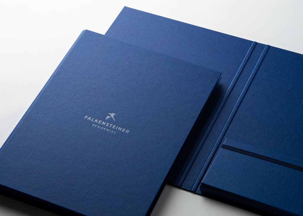 Blaue Präsentationsmappen mit silbergeprägtem Logo, Ablagefach und schwarzem Halteband