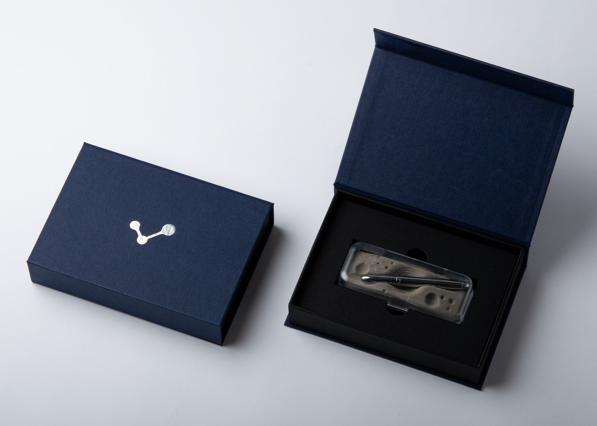Geschlossene und geöffnete blaue Magnetbox mit Produkt im schwarzen Inlay